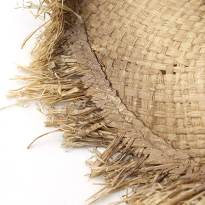 Handmade raffia cowboy hat with frayed fringe edges in natural straw color on white background
