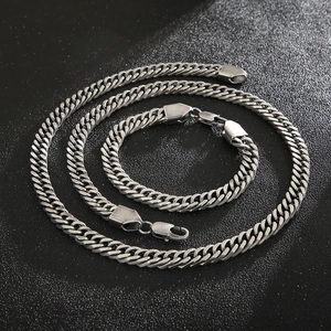 Macro view of silver stainless steel Cuban link necklace and bracelet set with lobster clasp
