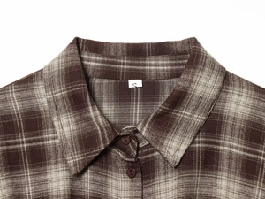 Close-up of brown plaid shirt collar with size S label on soft flannel fabric texture