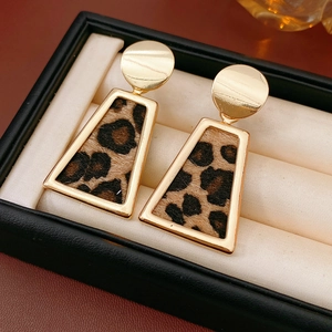 Vue macro de boucles d'oreilles dorées avec motif léopard et fausse fourrure en coffret