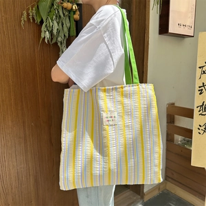 Dettaglio della borsa tote a righe con texture increspata e manici in tela verde