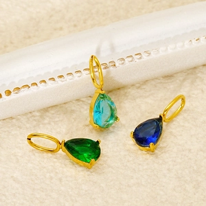 Close-up of teardrop zircon pendants in green and blue colors with gold plating
