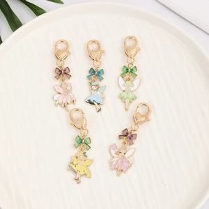 Five colorful fairy enamel bag pendants with heart-shaped lobster clasps on a plate