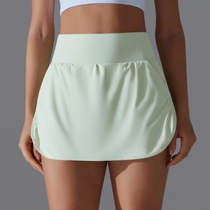 Detail view of high-waisted mint green tennis skirt with curved hem and elastic fabric
