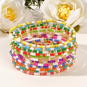 Colorful multi-layer seed bead bracelet set with gold accents on a clean beige background