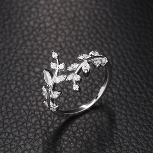 Macro shot of silver leaf ring with sparkling crystals on black leather texture