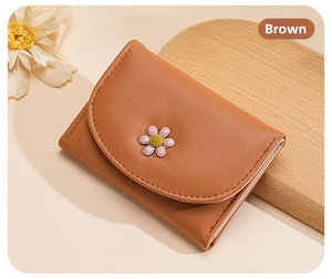 Detailed view of a brown leather wallet featuring a small daisy floral embellishment