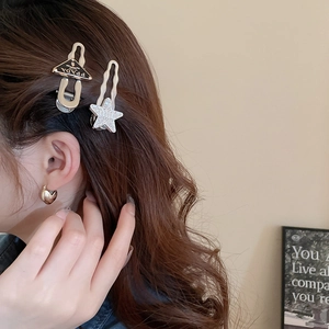 Detail of star-shaped rhinestone hairpin and black triangle clip on model's hair