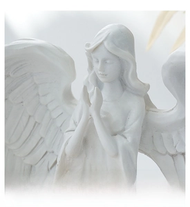 Close-up of white praying angel statue showing fine wing texture and nordic resin detail