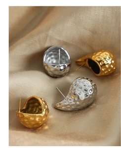 Detailed view of hammered texture drop earrings in gold and silver finish on silk