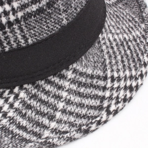 Macro shot of houndstooth plaid wool hat featuring a black decorative band and fine stitching
