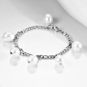 Macro shot of silver Figaro chain bracelet with six white pearls on reflective background