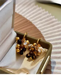 Detail of vintage tiger eye beaded tassel earrings on a green velvet jewelry gift box