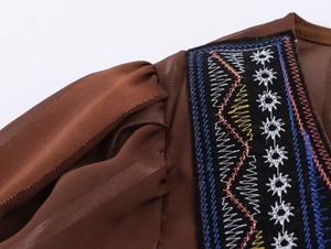 Détail d'une robe bohème montrant une broderie ethnique et la texture du tissu brillant