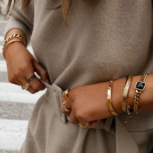 Dettaglio di bracciali e anelli placcati oro 18K con zircone bianco su sfondo in maglia