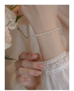Delicate 14k gold freshwater pearl bracelet worn by a model with elegant lace sleeve