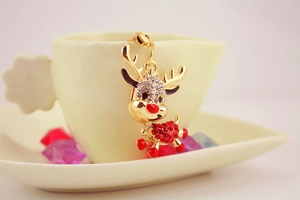 Close-up of a golden reindeer keychain with rhinestones and red enamel details on a cup