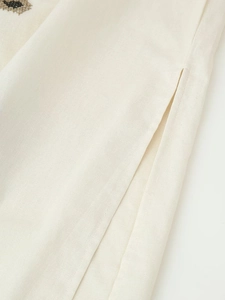 Detailansicht des Seitenschlitzes und der Baumwoll-Leinen-Struktur am bestickten Kleid