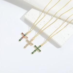 Detail of cross pendant necklace featuring heart-shaped colorful gemstones on gold chain