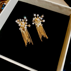 Detail of fireworks zircon earrings with golden tassels and pearls in a velvet box