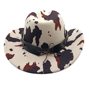 Close-up of cow print cowboy hat featuring a black leather band with metallic studs