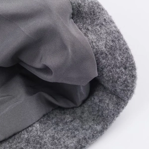 Detailed close-up of grey wool coat texture showing double-layered fabric and inner lining
