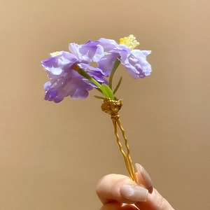 Vue détaillée d'une épingle à cheveux élégante en tissu violet avec tige dorée.