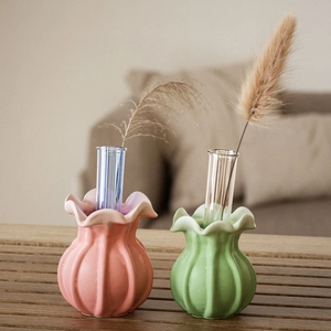 Detail of flower bud resin vases with glass inserts and dried reeds on wood table