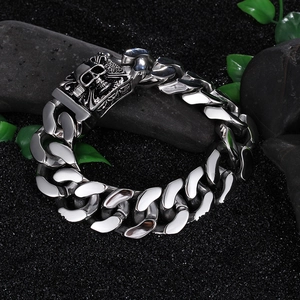 Dettaglio del bracciale a maglie con teschio in acciaio inossidabile su pietre scure