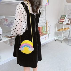 Close-up of yellow round crossbody bag featuring glitter rainbow and white cloud detail