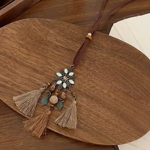 Detail of bohemian flower pendant with beige tassels and wooden beads on wooden tray