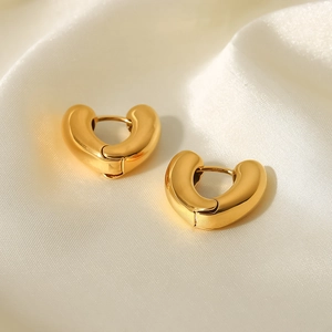 Detailed close-up of polished 18K gold-plated heart-shaped hoop earrings on silk