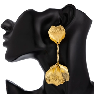 Detail of golden heart and leaf earrings with brushed metal texture on display