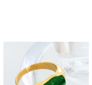 Vue macro d'une bague minimaliste dorée ornée d'une incrustation vert émeraude