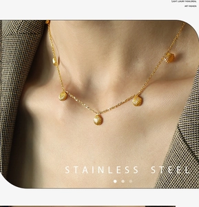 Detail showing five gold shell charms on a stainless steel chain worn with a blazer