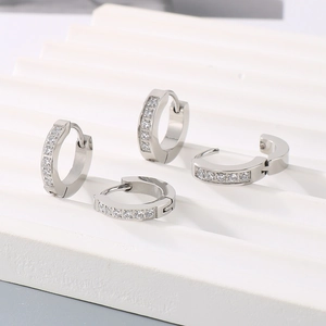 Macro shot of silver titanium steel huggie earrings with a single row of sparkling zircons