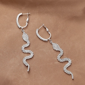 Elegant silver snake earrings with pavé crystals on premium brown satin background