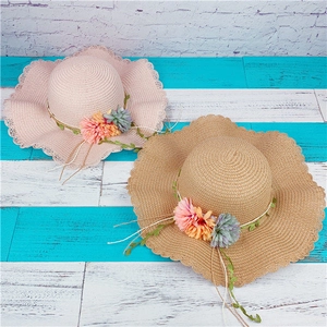 Detailed top view of wide brim straw sun hats featuring fabric flowers and vine decor