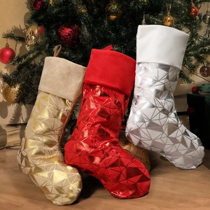 Set of large geometric shiny Christmas stockings in gold red and silver by festive tree