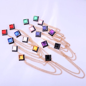 Close-up of golden tassel chain brooch with multi-colored square stones and black enamel