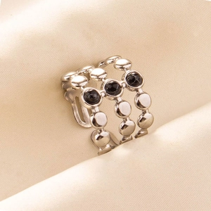 Detail of silver stainless steel ring with three black gemstones on silk fabric