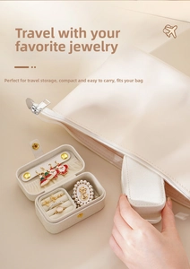 Close-up of portable jewelry box with ring slots and matching zipper pouch in beige leather