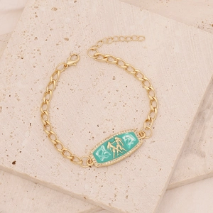 Detail of gold curb chain bracelet with green enamel Gemini zodiac pendant and zircons