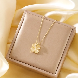 Detailed close-up of a 18K gold clover pendant with yellow cat-eye stones on a silk display