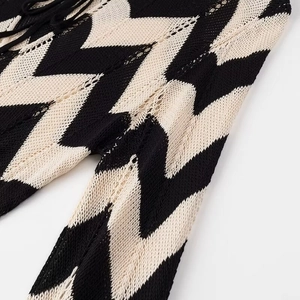 Detail eines hohlgestrickten Kleides mit schwarz-weißem Wellenstreifenmuster
