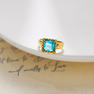 Detailed macro shot of vintage gold ring with large rectangular blue stone and twisted border