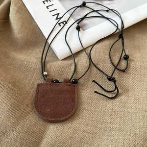 Close-up of vintage dark brown suede semi-circle pendant necklace with black lanyard