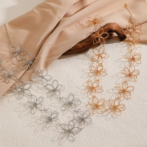 Detail of hollow floral necklaces in gold and silver finish over silk and wood