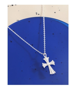 Close-up of a silver cross pendant necklace on a blue translucent pedestal base