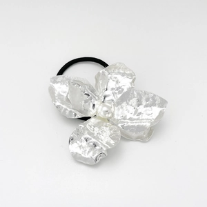 Detail of a black hair tie with silver hammered metal petals and a center white pearl